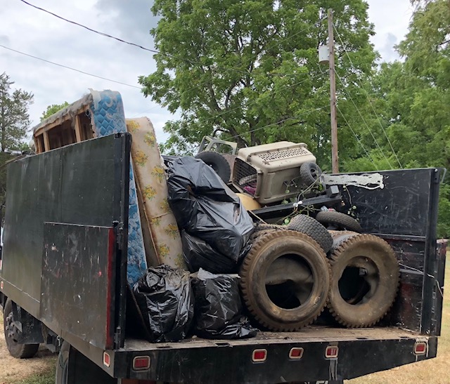 Truck filled with garbage bags, old mattresses, tires, and trash